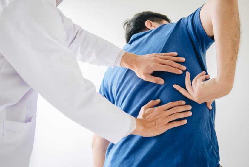 A physician demonstrates pain management using a spine model.